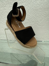 Load image into Gallery viewer, A single black wedge sandal with an ankle strap and espadrille-style braided sole, displayed on a clear acrylic stand against a textured white wall. The brand name 'Link' is visible on the tan footbed.
